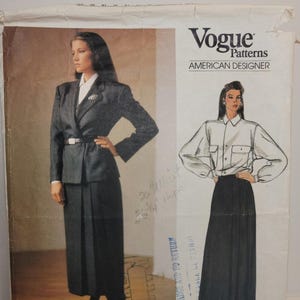 Peut inclure: Une pochette de patron de couture Vogue Patterns American Designer pour le modèle Ralph Lauren 1477. Le recto présente un blazer gris foncé avec une jupe longue assortie, ainsi qu'une chemise blanche à poches et une jupe longue foncée.