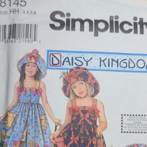 Pode incluir: Padrão de costura Simplicity com designs Daisy Kingdom. O padrão apresenta ilustrações de vestidos de menina e chapéus a condizer. Os vestidos têm padrões como cerejas e laços. O tamanho do padrão é HH 3,4,5,6.