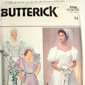 Puede incluir: Un patrón de costura Butterick con ilustraciones de tres diseños de vestidos de novia. Los diseños incluyen un vestido blanco con mangas abullonadas, un vestido lavanda con un sombrero a juego y un vestido blanco con velo. El número de patrón es 4766, talla 14.