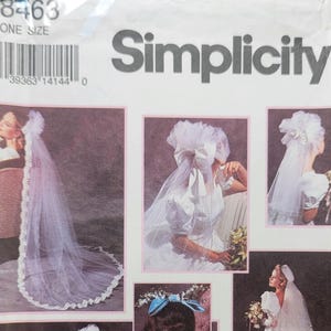 May include: Simplicity sewing pattern showing bridal gowns and veils. The image displays different wedding dress designs, including a long-sleeved gown with a veil and a dress with a large bow. The pattern includes multiple views of the bridal attire.