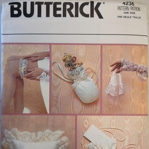 May include: Butterick pattern 4236 for wedding accessories. The envelope displays a garter, a small drawstring pouch with dried flowers, lace gloves, a square ring bearer pillow with lace trim and a ribbon bow, and a white fabric drawstring bag.