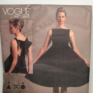 Könnte beinhalten: Eine Vogue Patterns Schnittmusterhülle für V1102, die ein schwarzes ärmelloses Kleid mit U-Boot-Ausschnitt und weitem Rock zeigt. Ein kleineres Bild zeigt die Rückansicht mit einer großen Schleife. Der Text umfasst VOGUE PATTERNS, V1102 und andreakatzobjects.