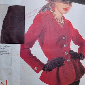 May include: Vogue Paris Original sewing pattern featuring a red jacket with silver buttons, a black skirt, and a large black hat. The pattern includes details for superb pockets. The text "WESSAINTLAURENT" and "VOGUE PATTERNS" are visible.
