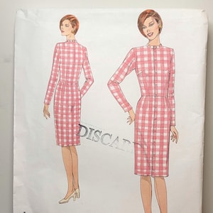 May include: A Vogue Patterns sewing pattern envelope for a dress, labeled 1004, featuring a pink and white gingham check print. The illustration shows a long-sleeved, knee-length dress with a button-front closure and a small ruffled collar.