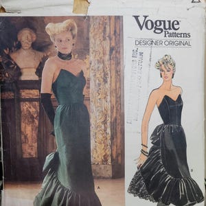 May include: Vogue Patterns Designer Original sewing pattern featuring a strapless evening gown with a ruffled skirt and a bow detail. The pattern includes a full-length photo of the gown and a line drawing.