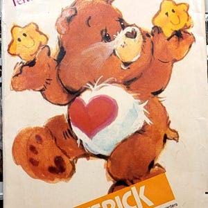 Könnte beinhalten: Eine Butterick-Schnittmusterhülle für einen Tenderheart Bear Dounout. Die Vorderseite zeigt einen braunen Bären mit einem roten Herz auf dem weißen Bauch, der zwei gelbe, lächelnde Sterne hält. Der Text enthält Care Bears, Butterick und MCMLXXXIII.