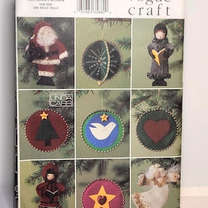 Op de afbeelding: Een Vogue Craft patroonhoes 7649 met illustraties van diverse kerstornamenten, waaronder een kerstmanfiguur, een koorzanger, een duif, een hart, een ster en een engel. Het ontwerp bevat gouden kralenranden op de ronde ornamenten.