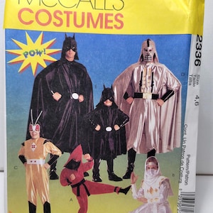 May include: A McCall's Costumes sewing pattern envelope, number 2336, featuring illustrations of various superhero and ninja costumes. The yellow and blue packaging displays five different costume designs labeled A through E, with the text POW! in a yellow starburst.
