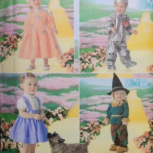 Peut inclure: Patron Simplicity avec des costumes d'enfants du Magicien d'Oz. Comprend Dorothy dans une robe rose, l'Homme de fer blanc en argent, une fille en robe bleue et l'Épouvantail en marron. Un chien est également présent.