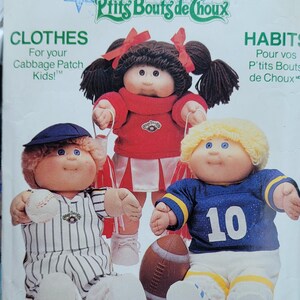 May include: A vintage Butterick pattern featuring Cabbage Patch Kids dolls in sports and cheerleader outfits. The pattern includes the text "CLOTHES" and "HABITS" with the Cabbage Patch Kids logo.