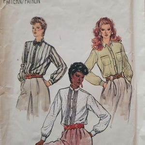 May include: A Vogue Patterns sewing pattern envelope 8377, size 10, featuring illustrations of three long-sleeved shirts with button-down fronts, collars, and cuffs, paired with trousers and belts. The designs include a striped shirt, a solid shirt, and a textured shirt.