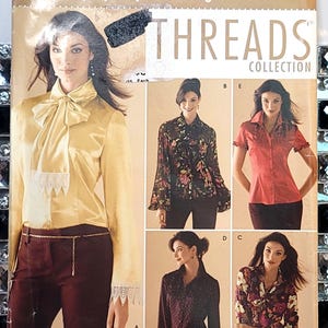 以下が含まれることがあります： Simplicity Threads Collectionの裁縫型紙封筒。5種類のブラウスデザインが掲載されています。表紙には、リボンとレースの袖口が付いた黄色のサテンブラウスと、花柄、水玉模様、無地の赤などのシャツのバリエーションが4種類表示されています。