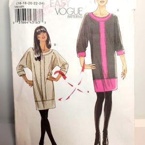 May include: A Very Easy Vogue Patterns sewing pattern envelope V8610 for sizes 16-18-20-22-24. The illustration shows two variations of a knee-length dress with three-quarter sleeves, one in beige and one in dark grey with bright pink trim.