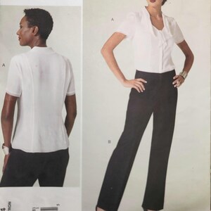 Op de afbeelding: Een naaipatroon van Anne Klein New York. Het toont een witte blouse met korte mouwen en een zwarte broek. Het patroonnummer is V1294, maat B5 (8-10-12-14-16). Het Vogue Patterns American Designer logo is zichtbaar. Een vrouw draagt de outfit.