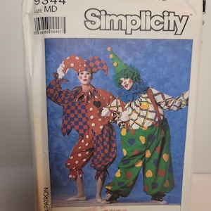 Pode incluir: Um envelope de molde de costura Simplicity, número 9344, tamanho MD. A frente apresenta dois trajes de palhaço: um com padrão de xadrez e bolinhas vermelhas e azuis, e outro com chapéu verde, gola azul e calças verdes com formas de coração.
