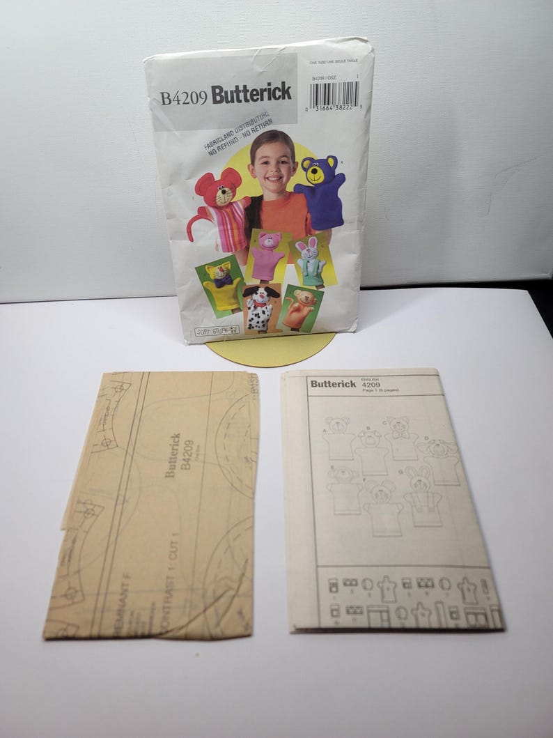 Butterick B4209 vintage hand puppet pattern envelope standing beside the uncut tissue and instruction booklet for the bear pig cat dog monkey mouse and bunny set