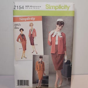 Op de afbeelding: Een Simplicity naaipatroon envelop, nummer 2154, voor een pak in 1960s retrostijl. De omslag bevat illustraties en foto's van een jasje, rok en blouse in koraalkleuren en ruitpatronen. Het bevat de maten H5 6, 8, 10, 12, 14.