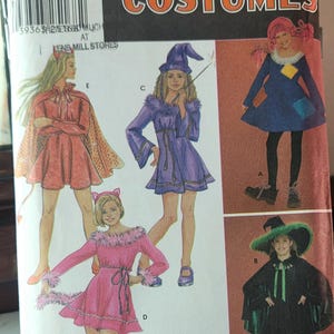 Pode incluir: Padrão de fantasias Simplicity com ilustrações de fantasias de Halloween, incluindo um diabo, uma bruxa, um gato e uma fada. O padrão é do tamanho A, para os tamanhos 7, 8, 10, 12 e 14. O padrão é de Betsy Kelly.