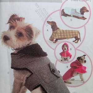 May include: A dog wearing a black and white patterned coat with a dark collar. The image also shows a pattern for dog coats and capes, with different styles and colors, including a red hooded cape and a plaid coat.