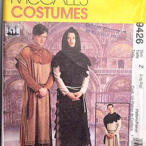 May include: A McCall's Costumes sewing pattern envelope 9426 for size Z, featuring illustrations of two outfits. One is a tan tunic with a brown hooded overlay and trim. The other is a light-colored robe with a black hooded overlay and rope belt.