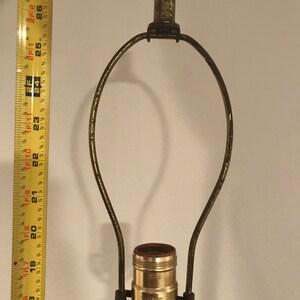 May include: A gold-toned lamp harp with a standard light bulb socket. The socket is labelled "LEVITON MODERN"