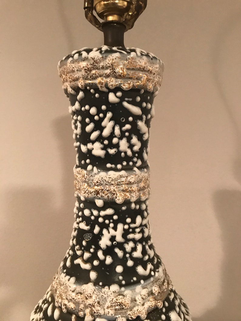 May include: A black ceramic table lamp with white and gold accents. The lamp has a textured surface with a speckled pattern.