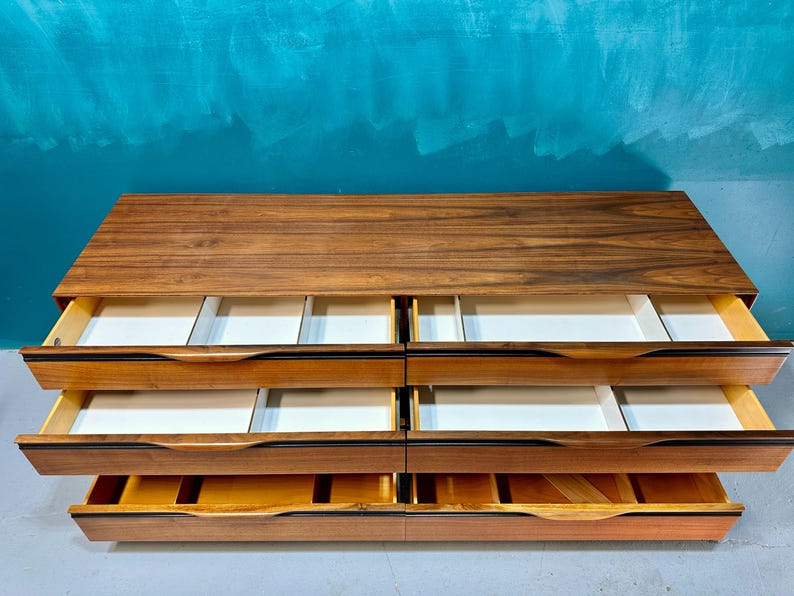 May include: A wooden dresser with six drawers. The drawers are open and the interior is white. The dresser is made of dark wood with a natural wood grain.