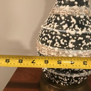 May include: A black and white ceramic lamp with a textured, speckled glaze. The lamp is 23 cm tall and has a brass base.