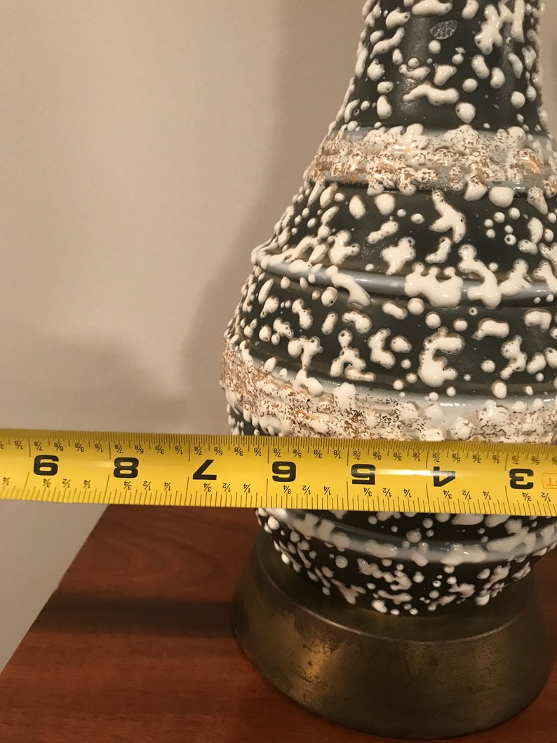 May include: A black and white ceramic lamp with a textured, speckled glaze. The lamp is 23 cm tall and has a brass base.