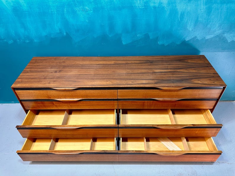 May include: A six-drawer dresser made of dark wood with a wood grain pattern. The drawers are open and show the light wood interior.