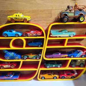 May include: A red and yellow shelf in the shape of the number 95, displaying a collection of toy cars. The cars are in various colours and designs. The shelf is made of wood and is a bright, playful addition to a room.