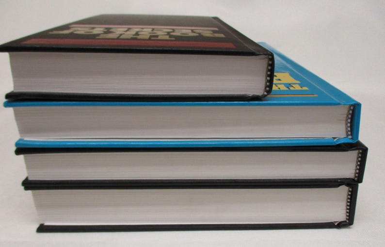 May include: A stack of three hardcover books with white pages and black or blue covers. The top book is black with red text, the middle book is blue, and the bottom book is black.