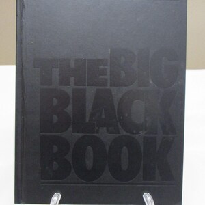 May include: A black book with the title "THE BIG BLACK BOOK" embossed on the cover. The book is rectangular and appears to be hardcover. The text is in a bold, sans-serif font.