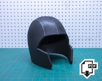 May include: A matte black helmet with a smooth, rounded dome and a wide, open face cutout. The helmet features a seam running vertically along the center of the top and has thick, structured sides that extend downward to frame the face area.