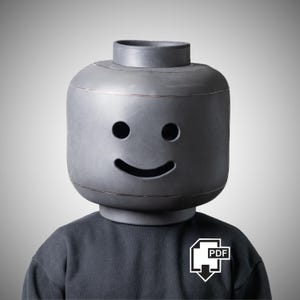 May include: A person wearing a large, grey Lego-style head with a smiling face. The person is wearing a dark grey sweatshirt with a white PDF icon on the chest.