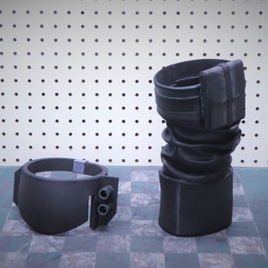 Puede incluir: Disfraz de utiler&iacute;a negro de dos piezas. Una pieza es un brazalete con dos peque&ntilde;os cilindros, la otra es una pieza cil&iacute;ndrica alta con un accesorio rectangular. Las piezas est&aacute;n hechas de un material negro mate.