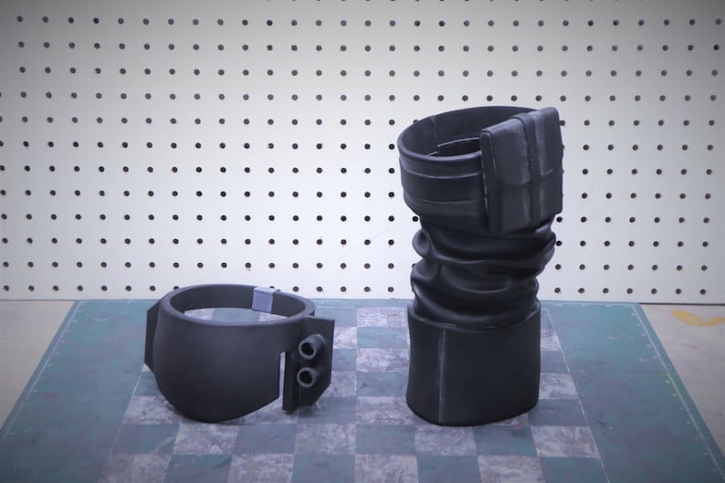 Puede incluir: Disfraz de utiler&iacute;a negro de dos piezas. Una pieza es un brazalete con dos peque&ntilde;os cilindros, la otra es una pieza cil&iacute;ndrica alta con un accesorio rectangular. Las piezas est&aacute;n hechas de un material negro mate.