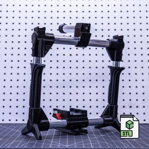 May include: A black 3D printed camera rig with adjustable arms and a sliding base. The rig is designed to hold a camera and other accessories. STL file included.