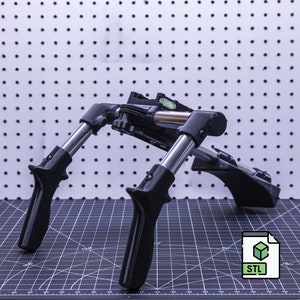 May include: A black 3D printed adjustable camera stand with two handles and a level. The stand is on a black and white grid surface. STL file.