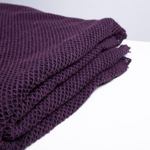 May include: A folded purple knitted blanket with a waffle-like texture.