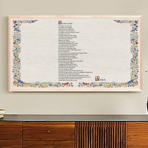 Könnte beinhalten: Ein gerahmter Druck des Nicaenum mit einem dekorativen floralen Rahmen. Der Text ist in schwarzer Tinte auf weißem Hintergrund. Der Rahmen ist in hellem Holzton.