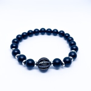May include: A black beaded bracelet with a black and silver sphere charm.