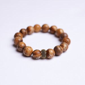May include: A brown wood bead bracelet with a gold and black accent bead.