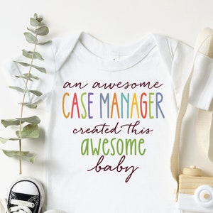May include: White baby onesie with the text "An awesome case manager created this awesome baby" in rainbow colors.