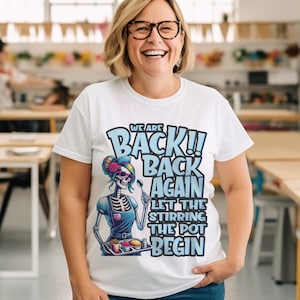 May include: White t-shirt with a graphic of a skeleton wearing a chef's hat and holding a tray of food. The text on the shirt reads "We are Back!! Back Again Let the Stirring the Pot Begin".