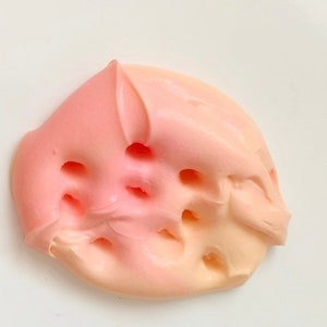 May include: Close-up of a pink and peach colored whipped cream frosting with holes in it.