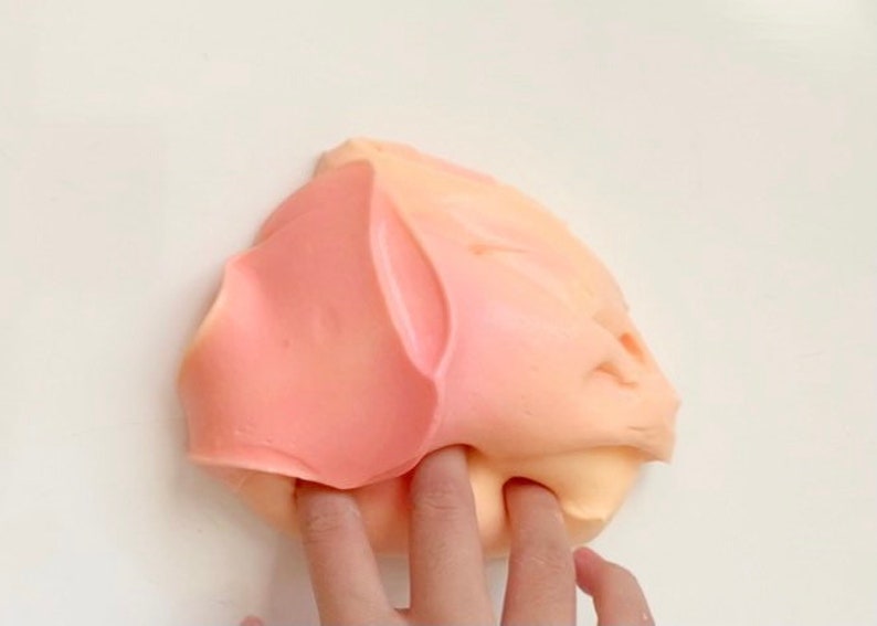 May include: A close-up of a pink and orange slime being stretched and pulled by a finger.