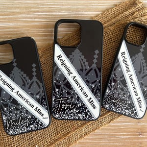 May include: Three black phone cases with a silver glitter background and a white sash that says "Reigning American Miss" with a name on each case. The names are Miley, Tom, and Cadence.