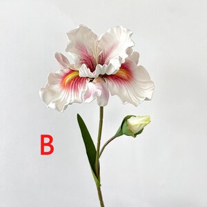 May include: A single white and pink artificial iris flower with a yellow center and a green stem. The flower has a bud on the stem. The flower is on a white background.
