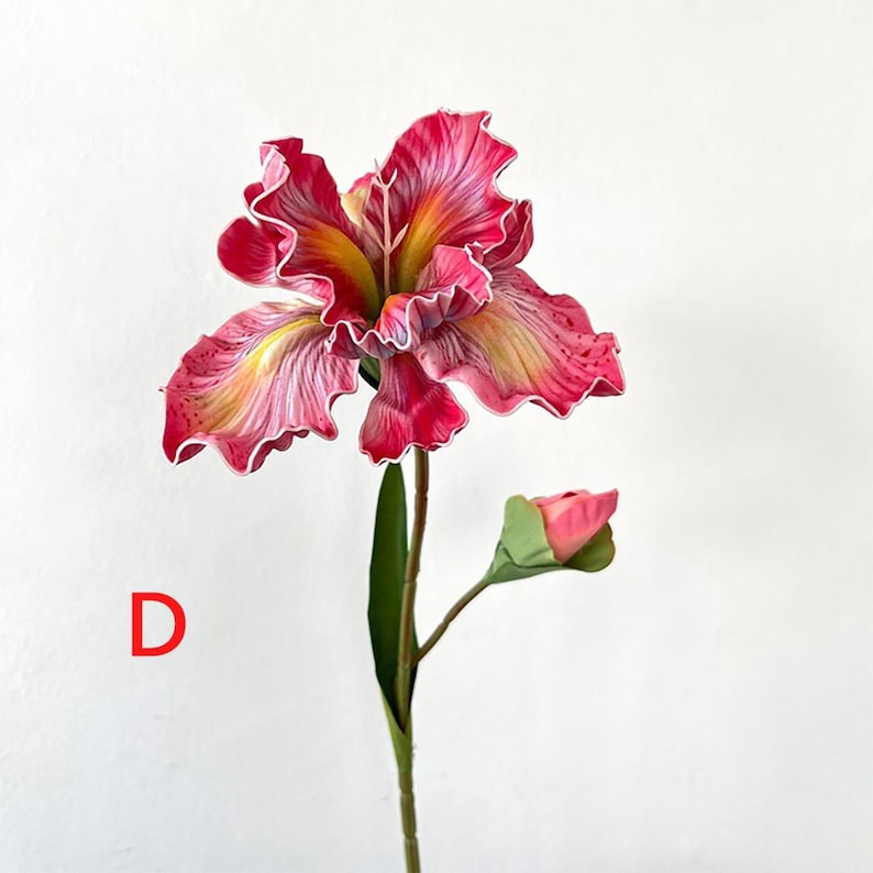 May include: A single pink and yellow artificial iris flower with a bud. The flower has a ruffled texture and is on a green stem.